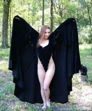 Redhead amateur Amber Lily models nude in a forest draped in a black cape on dochick.com