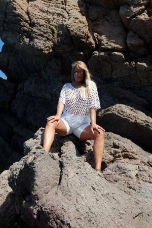 Blonde amateur Sweet Susi exposes her tits and ass on a rocks by the sea on dochick.com