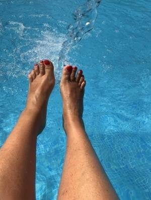 Mature woman Sweet Susi dips her painted toenails into a swimming pool on dochick.com