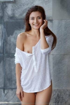Petite teen divests herself of a white shirt to pose nude in and out of a pool on dochick.com