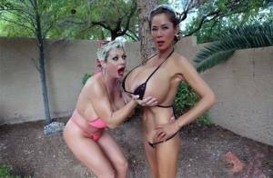 Big titted older women Claudia Marie and Minka kiss outdoors in skimpy bikinis on dochick.com