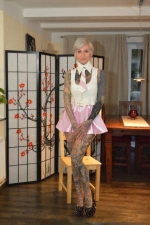 Tattooed platinum blonde Miss Francine models a raincoat over a latex dress on dochick.com
