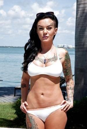 Tattooed whore Lolo Luscious exposing big hooters in swimming pool on dochick.com