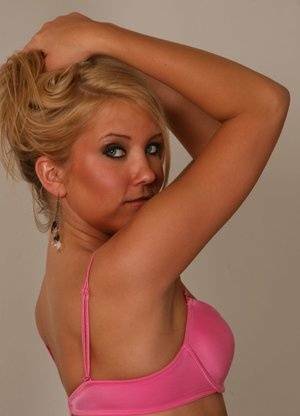 Blonde amateur Jocalynn piles up her hair before getting naked on a bed on dochick.com