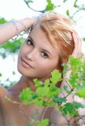 Adorable redhead Violla A displays her naked teen body atop a rock outdoors on dochick.com