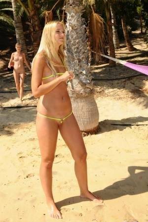Natural blonde takes off her bikini to get totally naked on a beach on dochick.com
